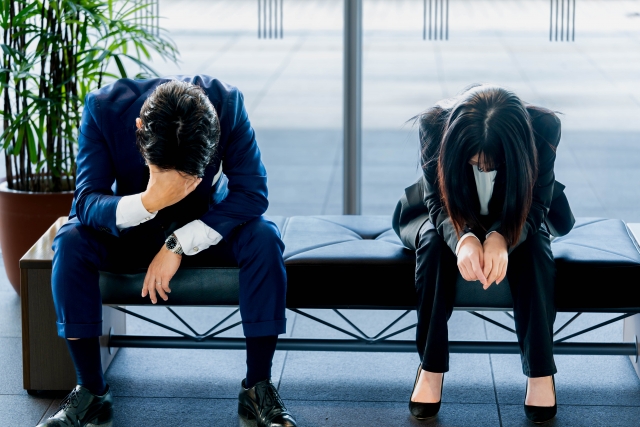 下を向いて座っている会社員の男女