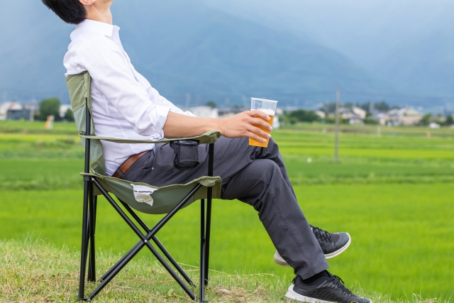 一人で椅子に座って野外でビールを飲んでいる男性