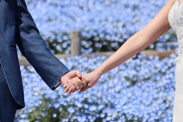 青い花の背景でウエディングドレスで手を繋いている男女