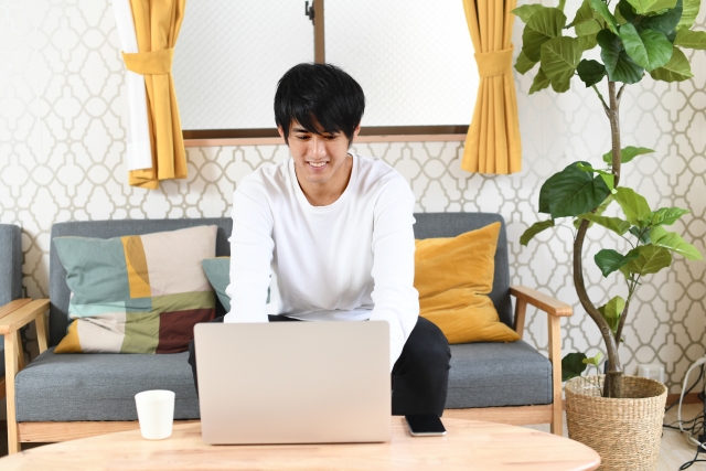 家でパソコンで勉強をしている男性