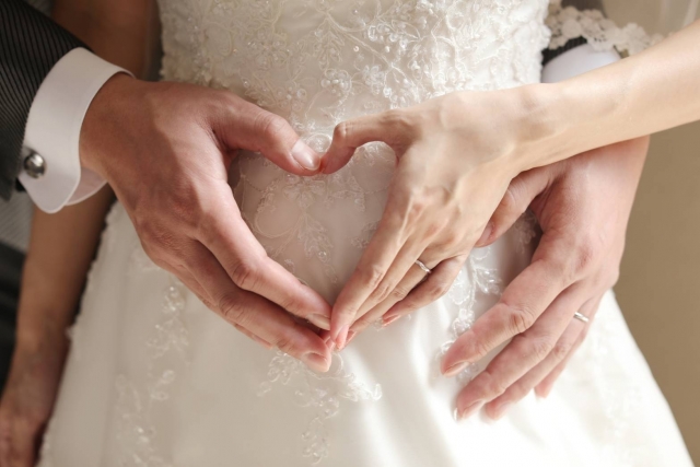 ウェディングドレスを着た女性とハートマークを作った男性