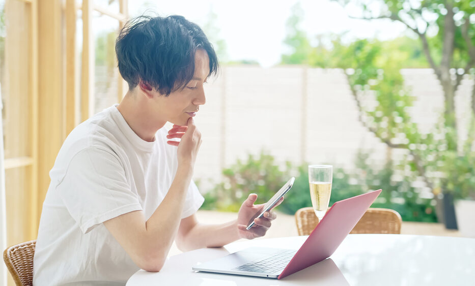 朝庭が見える場所でパソコンで作業をしている男性