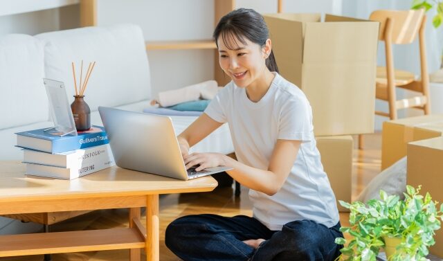 段ボールに囲まれながらパソコンで仕事をしている女性