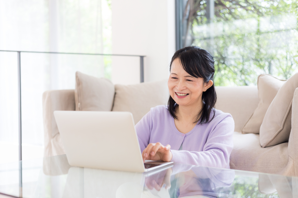 笑顔でパソコンに向かって作業をしている女性