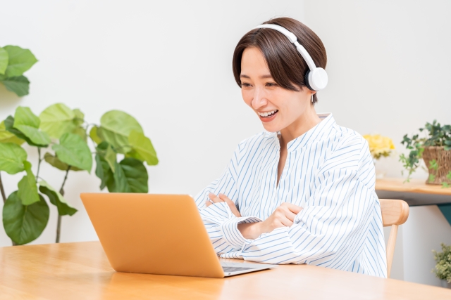 ヘッドフォンとパソコンで家で仕事をしている女性